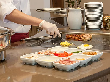 Cuisinier préparant un œuf au buffet petit déjeuner de l'Enztalhotel