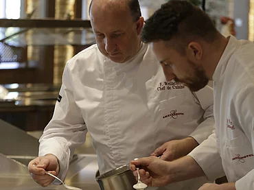 Deux cuisiniers préparant un plat principal à l'hôtel gastronomique Enztalhotel