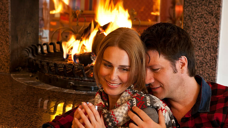 Couple se réchauffant avec un thé près de la cheminée de l'Enztalhotel en Forêt-Noire