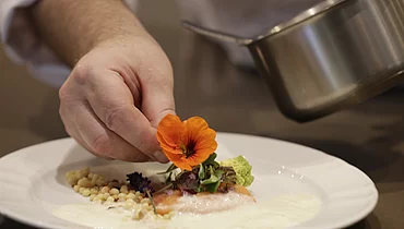 Deux cuisiniers préparant un plat principal à l'hôtel gastronomique Enztalhotel