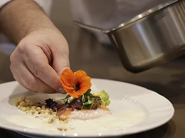 Deux cuisiniers préparant un plat principal à l'hôtel gastronomique Enztalhotel
