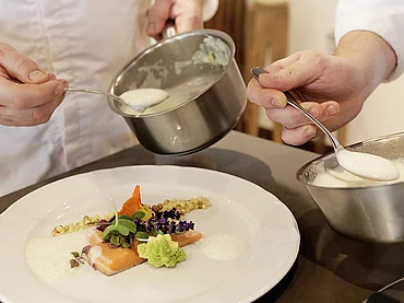 Deux cuisiniers préparant un plat principal à l'hôtel gastronomique Enztalhotel