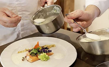 Deux cuisiniers préparant un plat principal à l'hôtel gastronomique Enztalhotel
