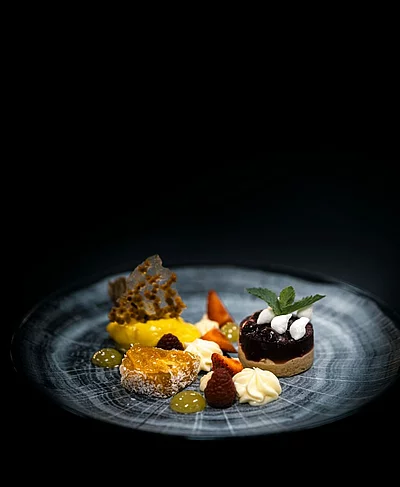 Aus unserer Pâtisserie Nougat-Sauerkirsch-Törtchen mit Aprikosensülze, feiner Kokoscreme und erfrischendem Passionsfrucht-Sorbet